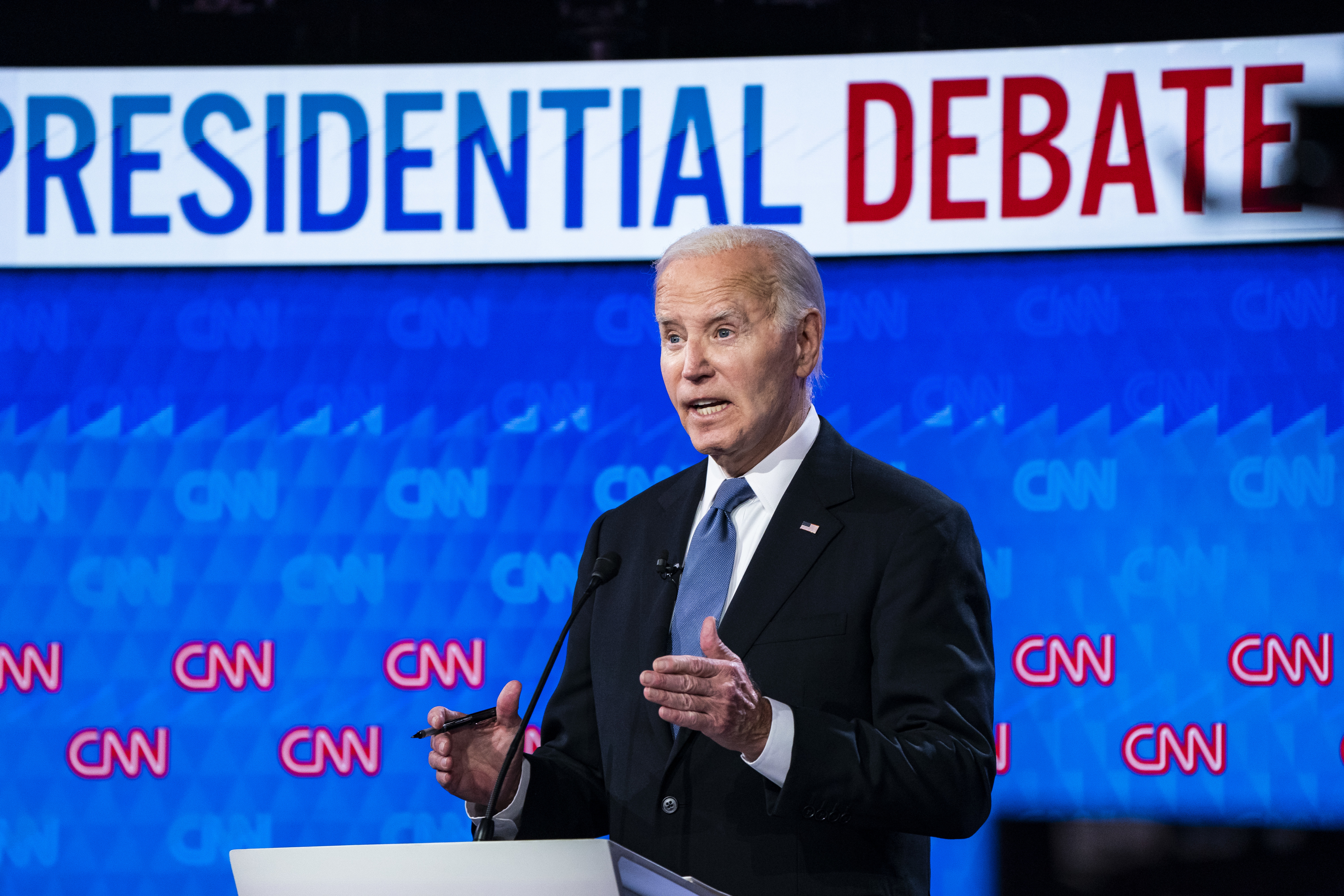 Joe Biden speaks at a podium during a CNN Presidential Debate. The background features a &quot;Presidential Debate&quot; sign