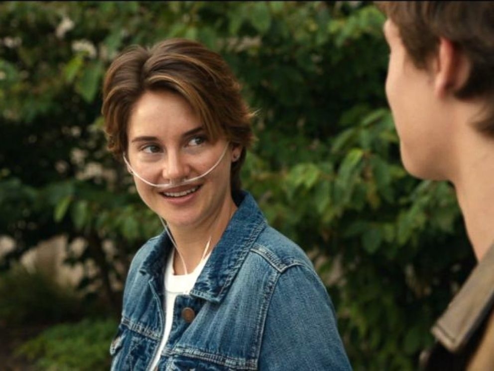 Shailene Woodley in a denim jacket with a nasal cannula smiles at Ansel Elgort in a scene from &quot;The Fault in Our Stars.&quot; Elgort is facing her