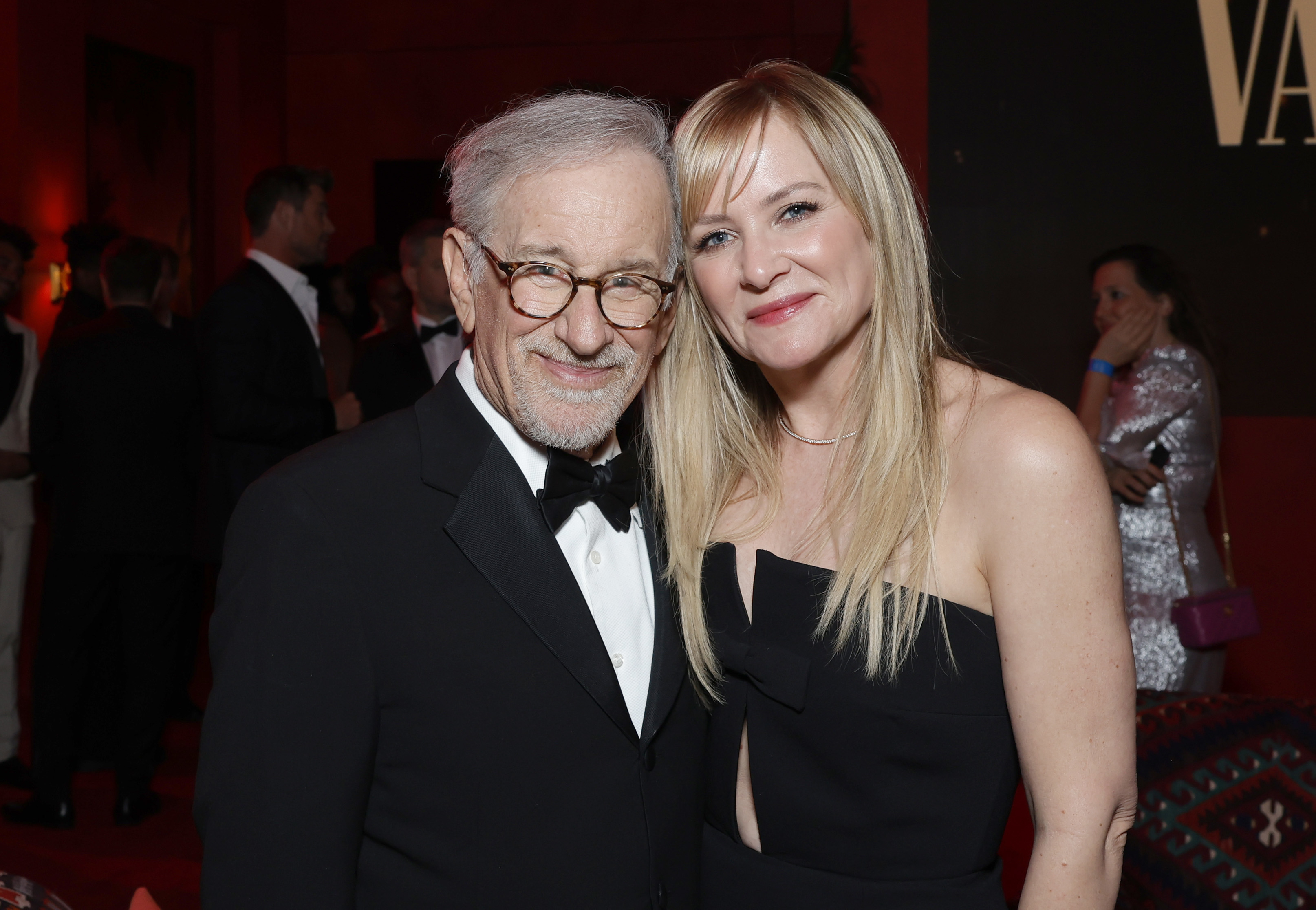 Steven Spielberg, in a classic tuxedo, and Jessica Capshaw, in a stylish black dress, pose together at a red carpet event
