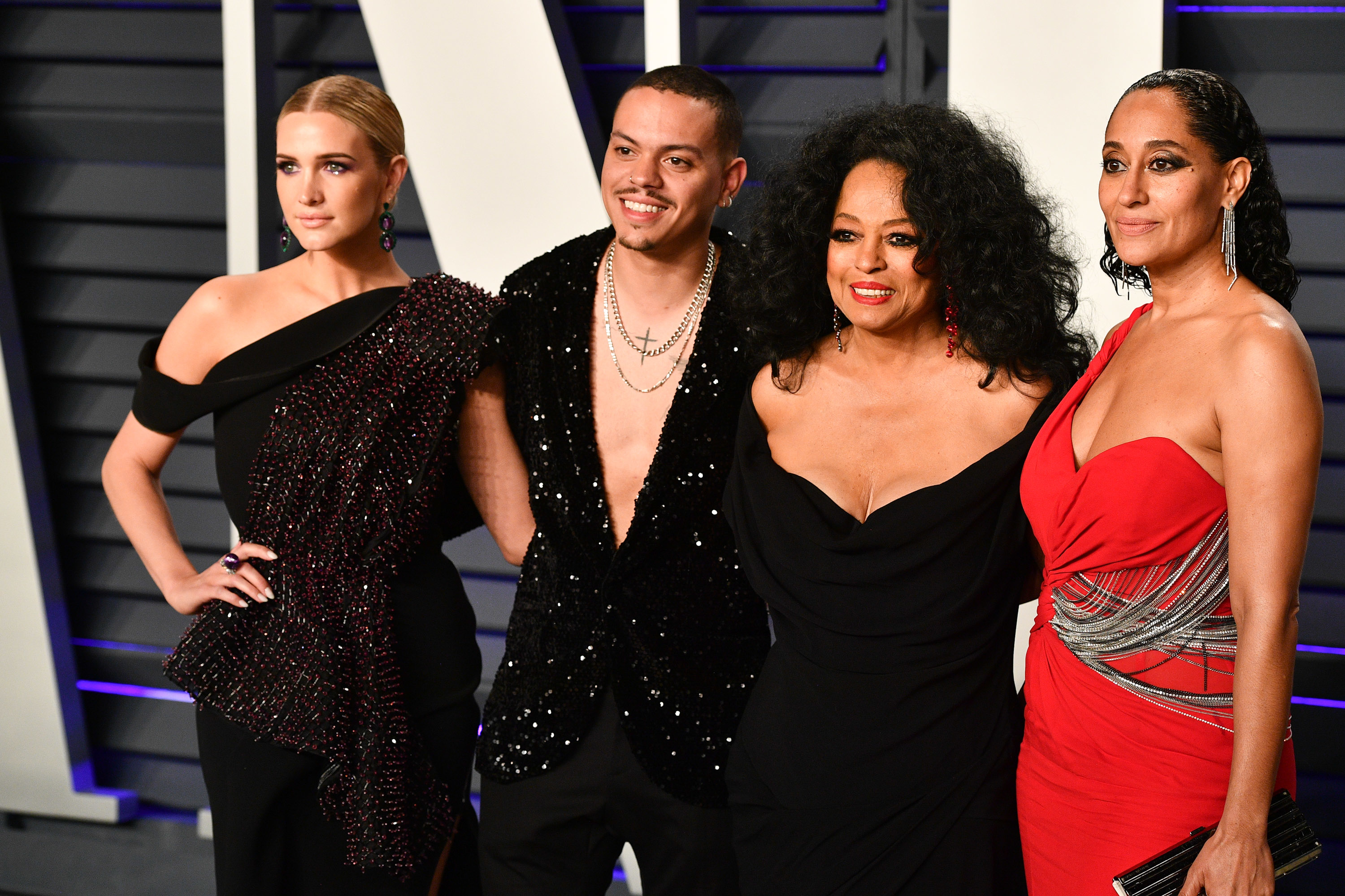 Ashlee Simpson, Evan Ross, Diana Ross, and Tracee Ellis Ross pose together. Ashlee wears a stylish one-shoulder dress, Diana in a sparkling outfit, and Tracee in a chic gown