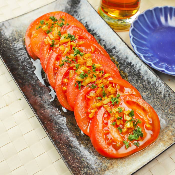 陶器の皿に盛られた新鮮なトマトのスライスが並んでいます。