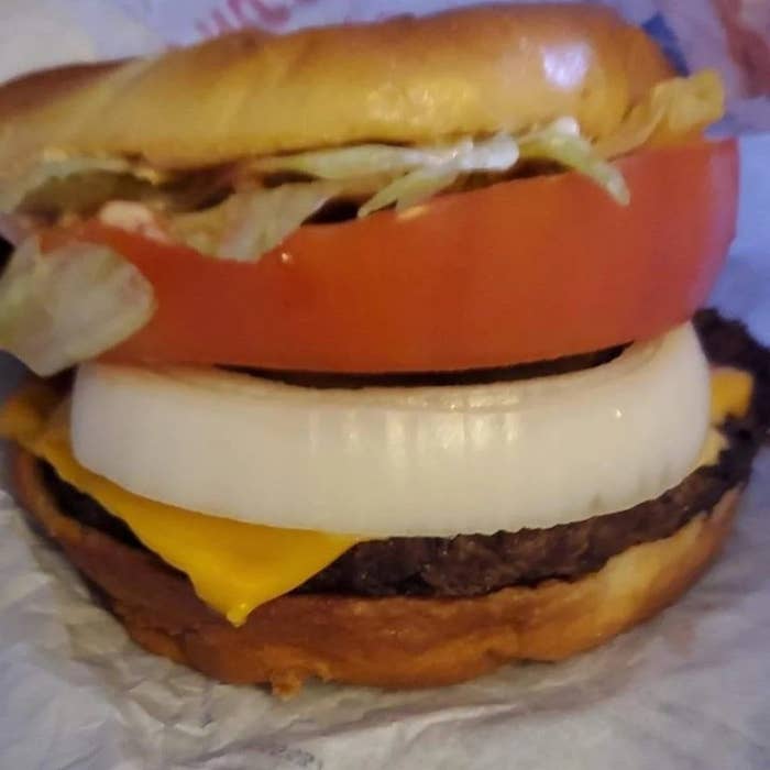 Close-up of a cheeseburger with lettuce, tomato, onion, cheese, and a beef patty