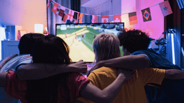 Four people watching soccer on the television