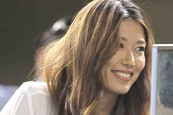 女性が白いシャツを着て微笑んでいる。