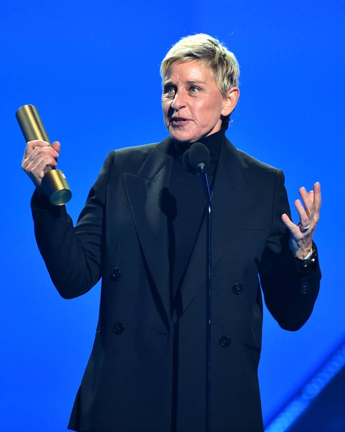 Ellen DeGeneres wearing a suit jacket, holding award and speaking on stage