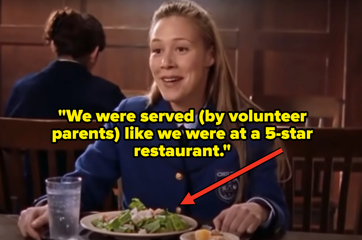 Two people standing in a hallway near lockers, one facing the camera and smiling, the other looking on. Names not known