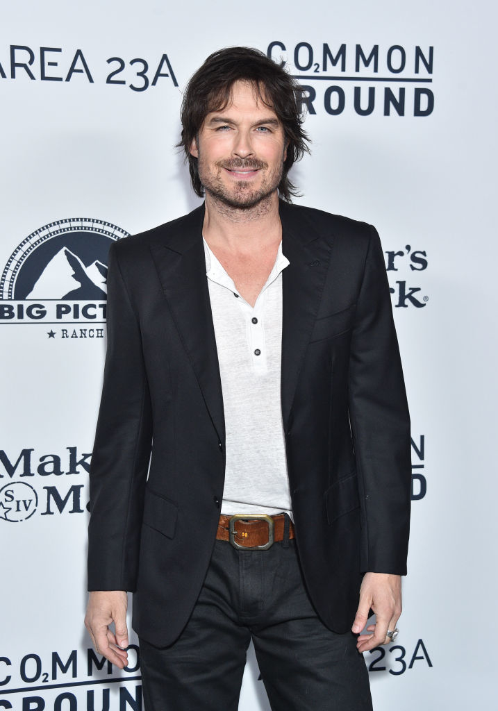 Ian Somerhalder in a casual wshirt under a dark suit jacket, dark jeans, and a belt, posing at an event in front of a step-and-repeat backdrop