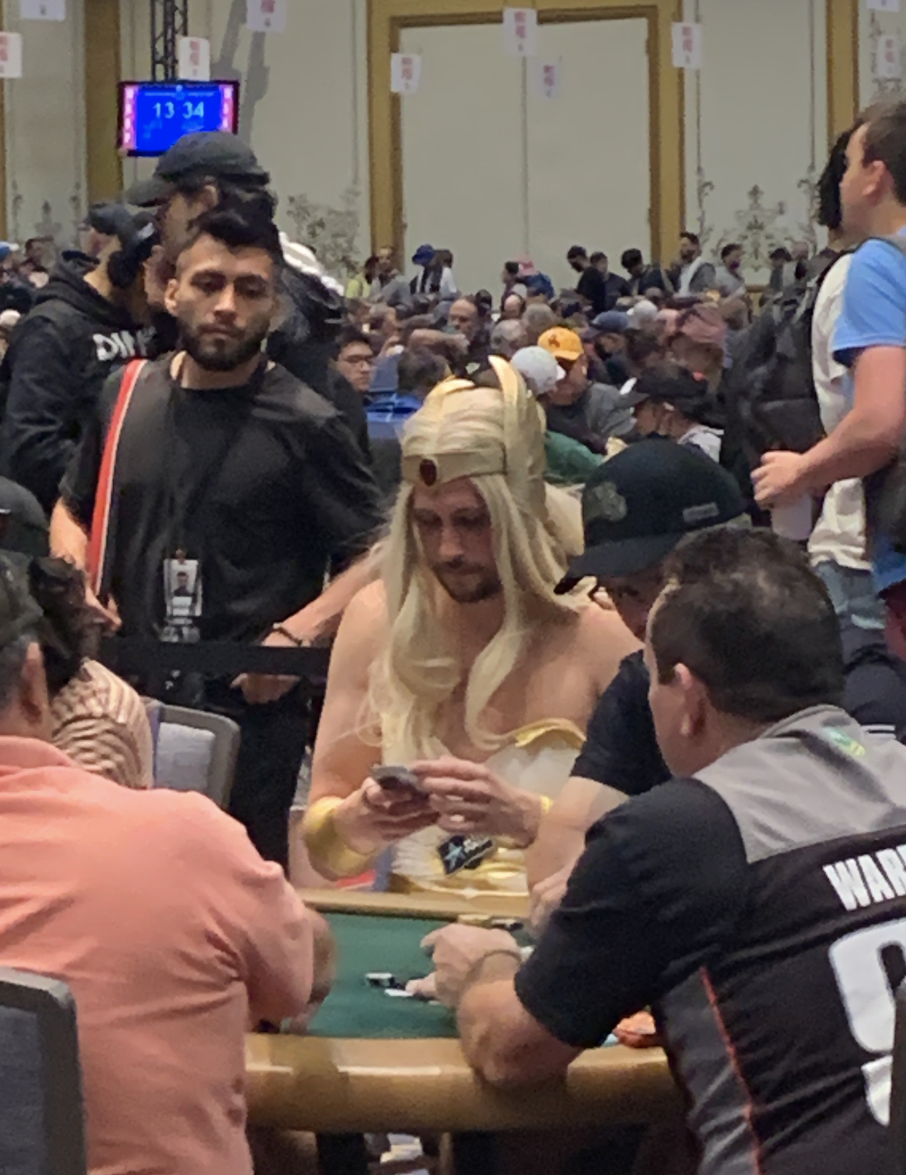 A game room filled with people playing poker. One player, dressed as Elsa from Frozen, is concentrating on their cards