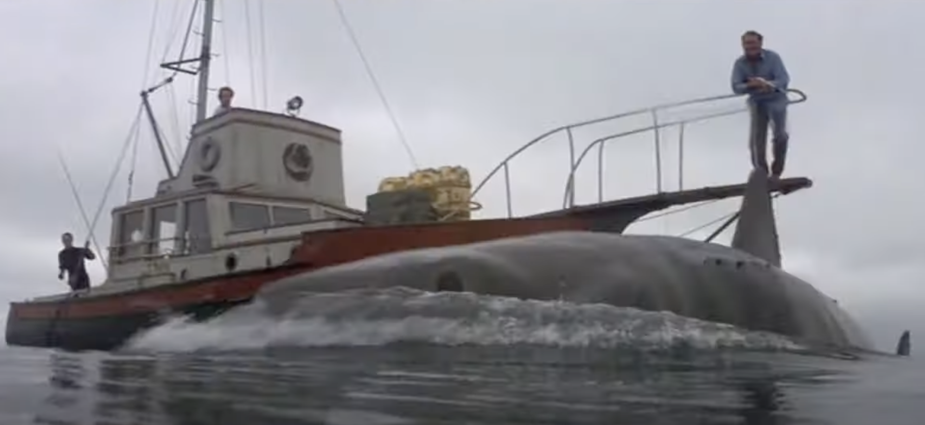 Three people on a small boat face a massive shark in the ocean, reminiscent of a scene from "Jaws."