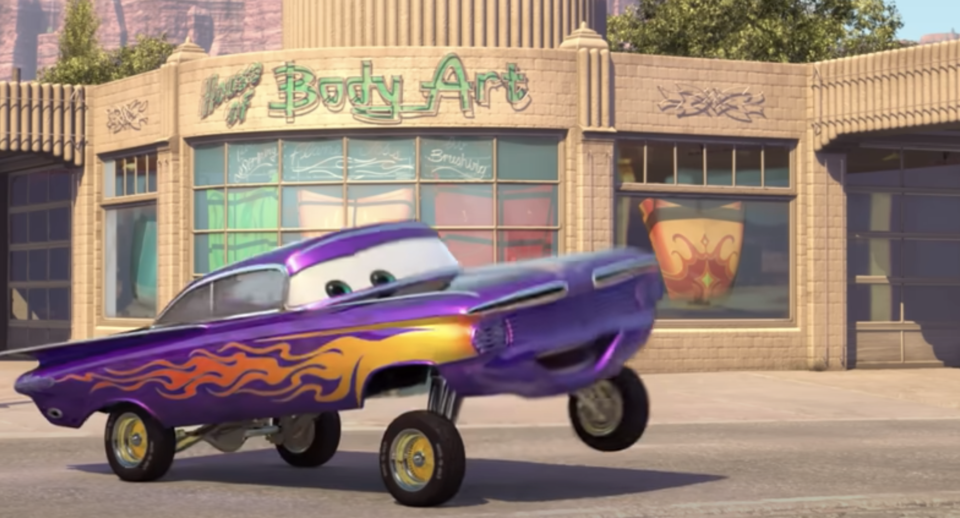 Ramone, a car character from the movie Cars, poses in front of his auto shop, Ramone's House of Body Art, performing a wheelie