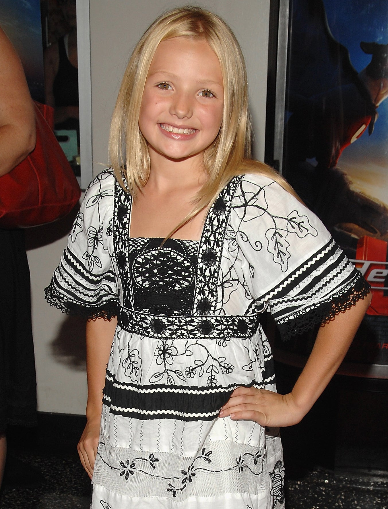 Young girl on the red carpet wearing a black and white floral dress over white pants
