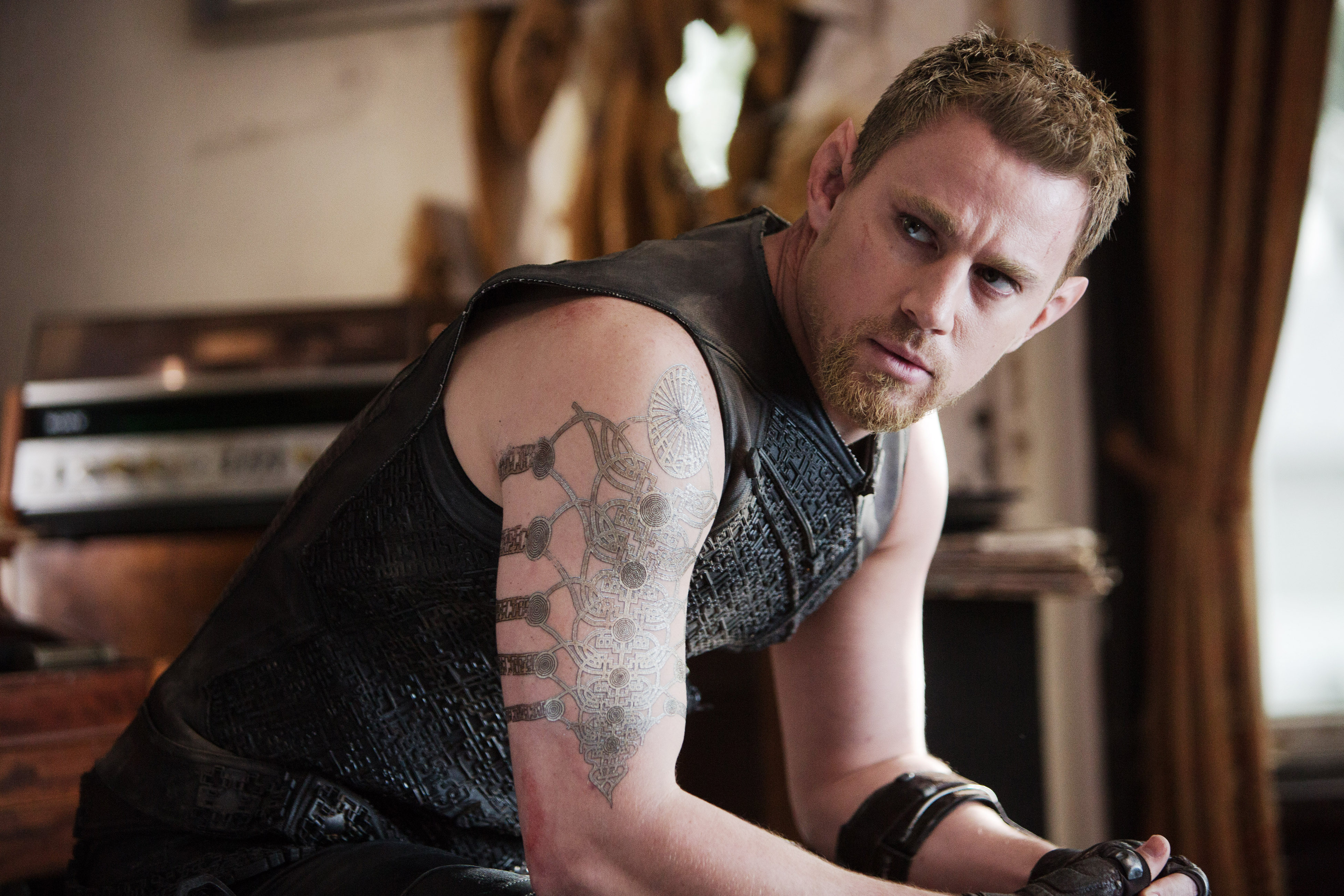 Channing Tatum wearing a dark vest with a tattoo on him arm in a scene from &quot;Jupiter Ascending&quot;