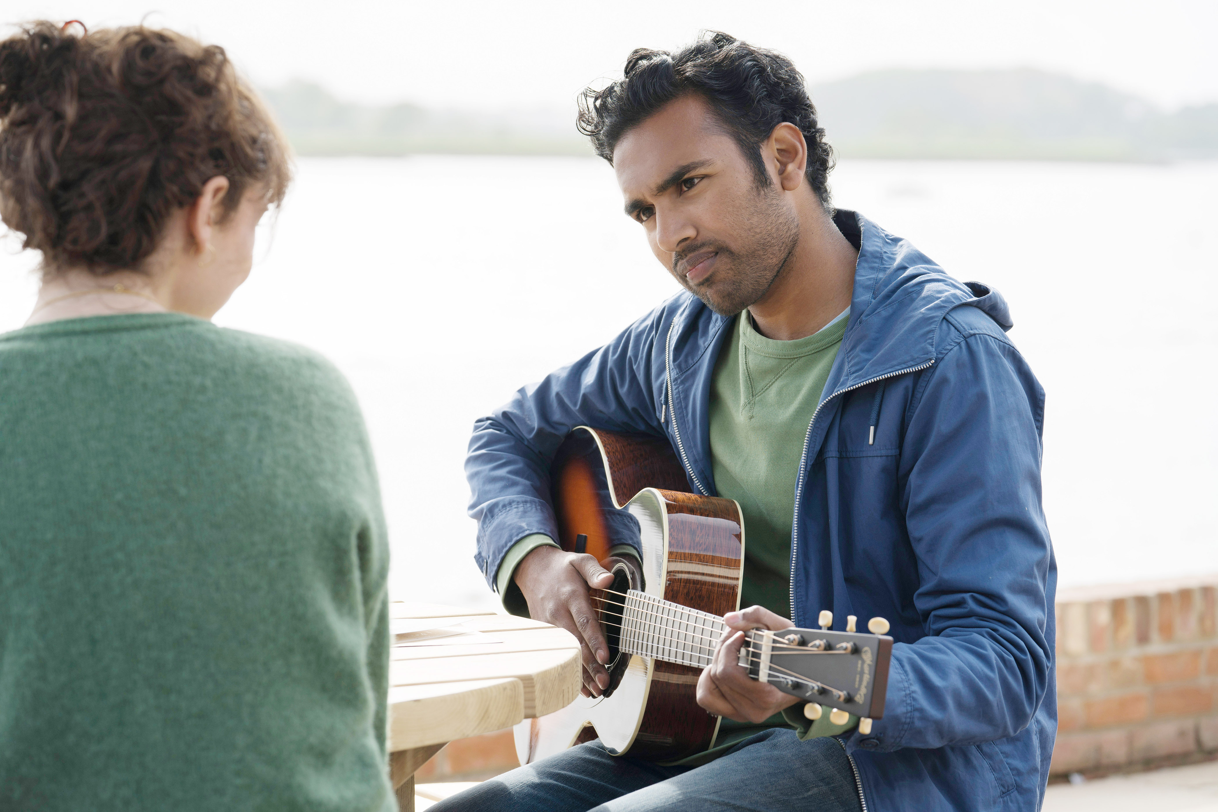 Lily James stares at Himesh Patel who is playing a guitar in a scene from &quot;Yesterday&quot;