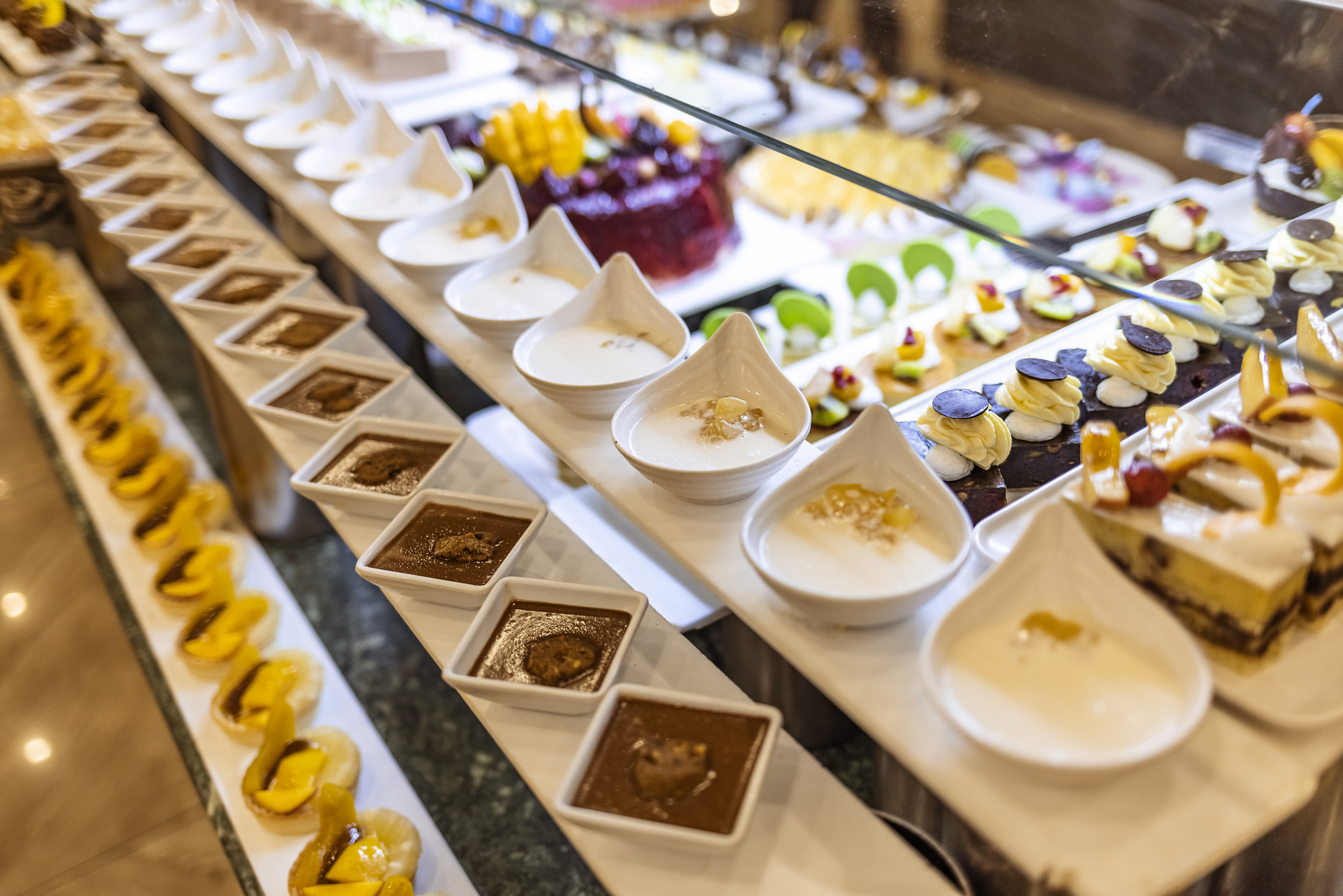 A lavish dessert buffet with various pastries, puddings, cakes, and custards arranged in a sophisticated presentation