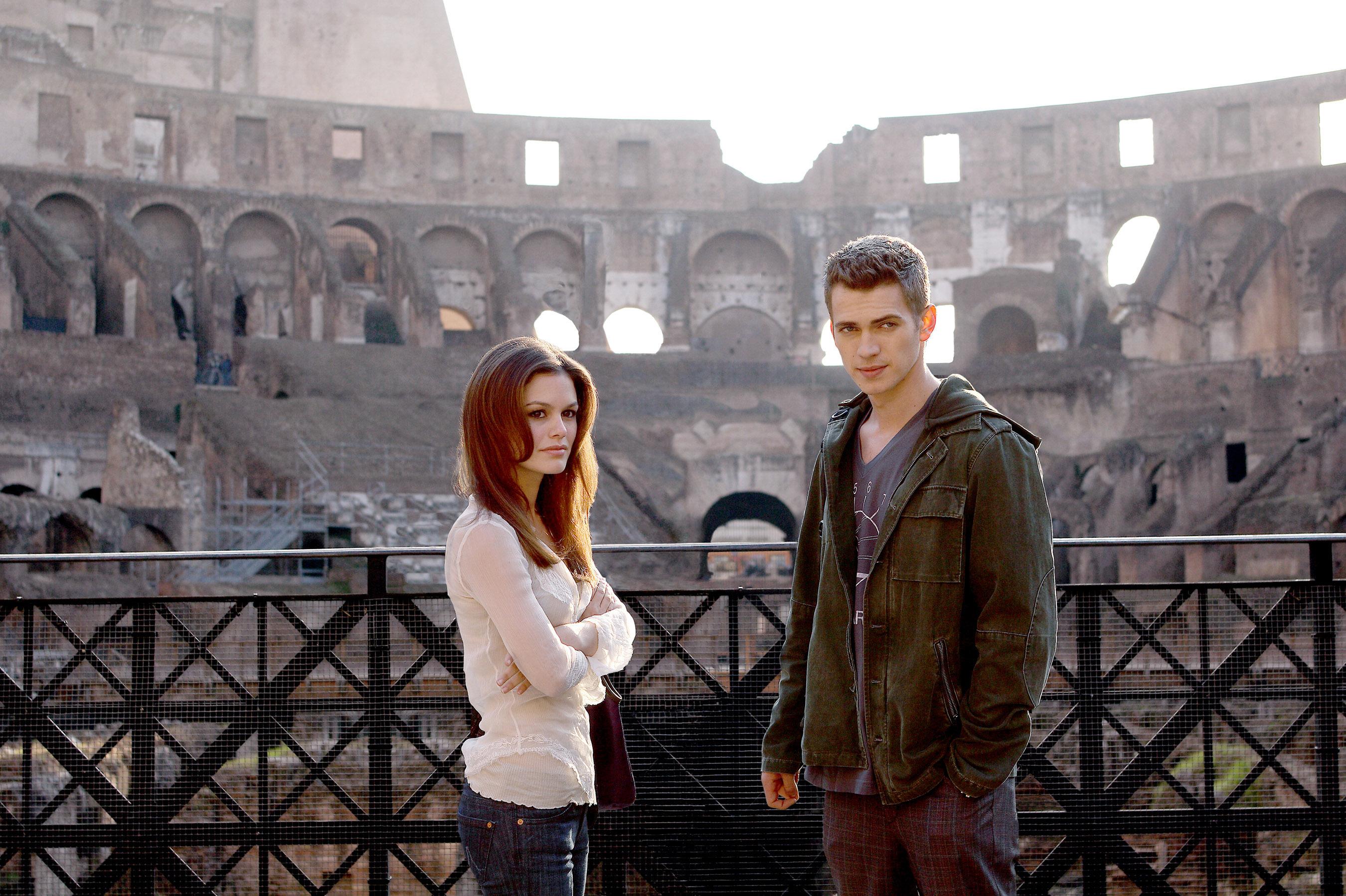 Rachel Bilson and Hayden Christensen stand in front of the Roman Colosseum. Rachel is wearing a white blouse, and Hayden has on a casual jacket and pants in a scene from &quot;Jumper&quot;