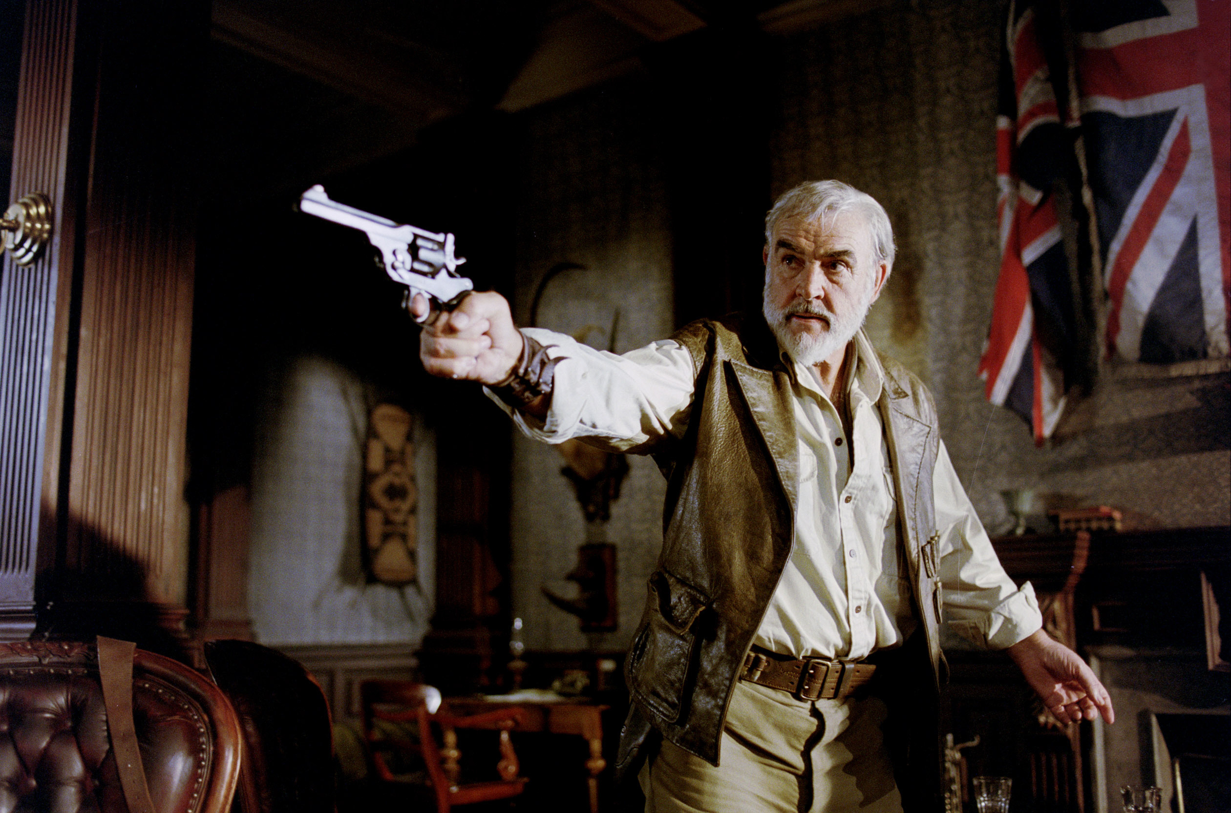 Sean Connery aiming a revolver inside a room decorated with British flags and old furnishings in a scene from &quot;The League of Extraordinary Gentlemen&quot;