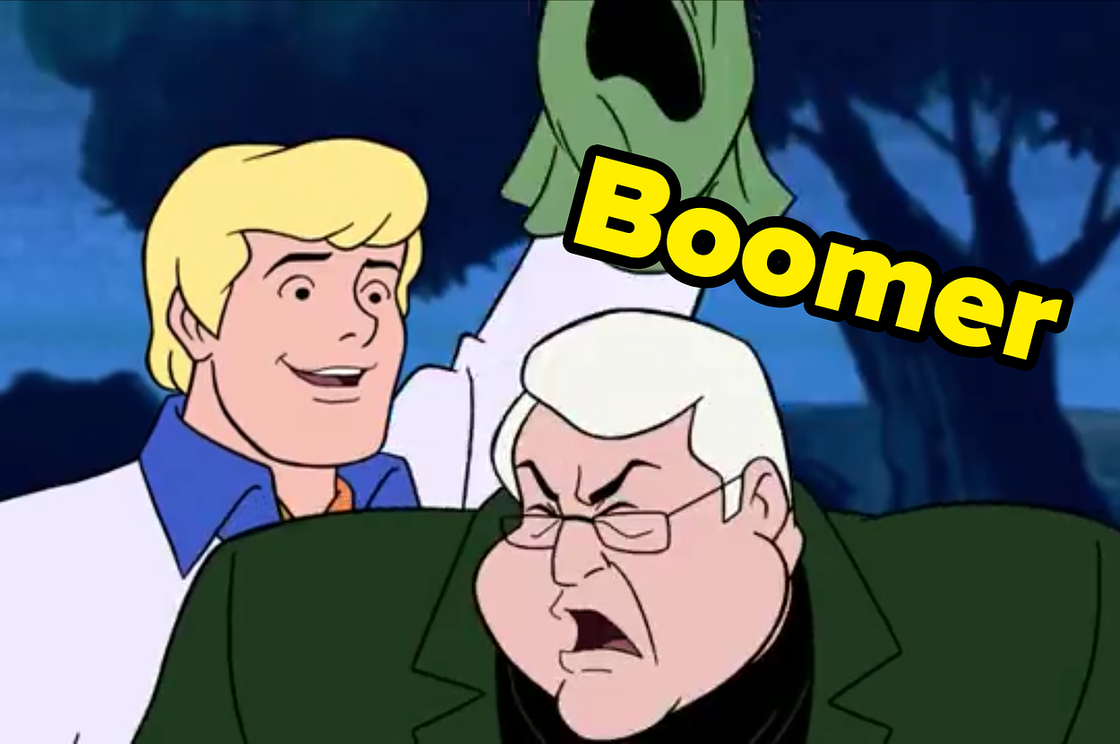 Fred from Scooby-Doo unmasks a villain in glasses and a green jacket, revealing the word "Boomer" above the villain's head