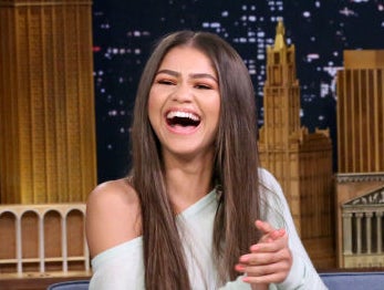 Zendaya laughs while sitting next to Jimmy Fallon on his talk show. Jimmy shows a photo on a tablet to the audience