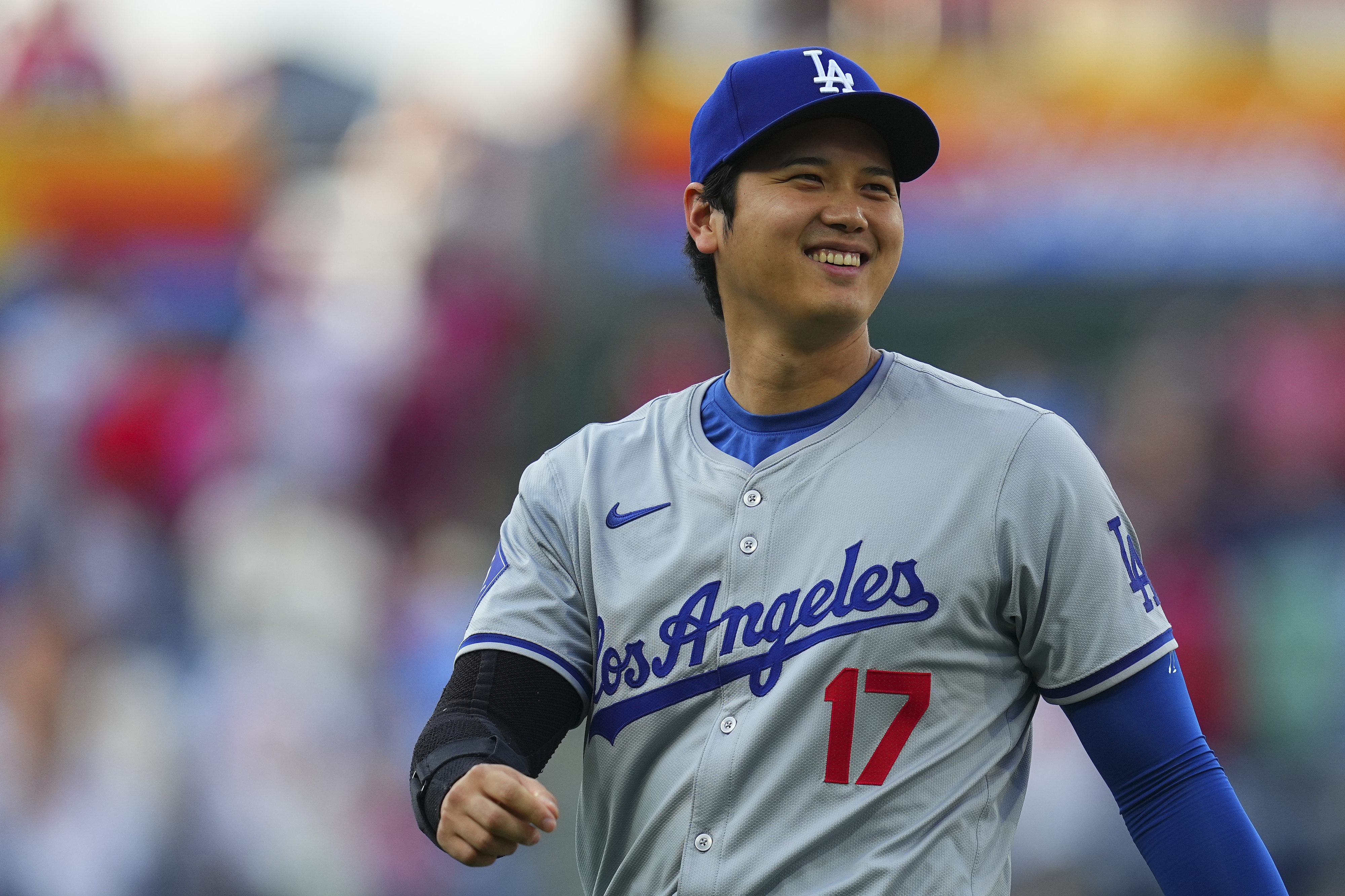Shohei Ohtani smiles while wearing a Los Angeles Dodgers baseball uniform during a game