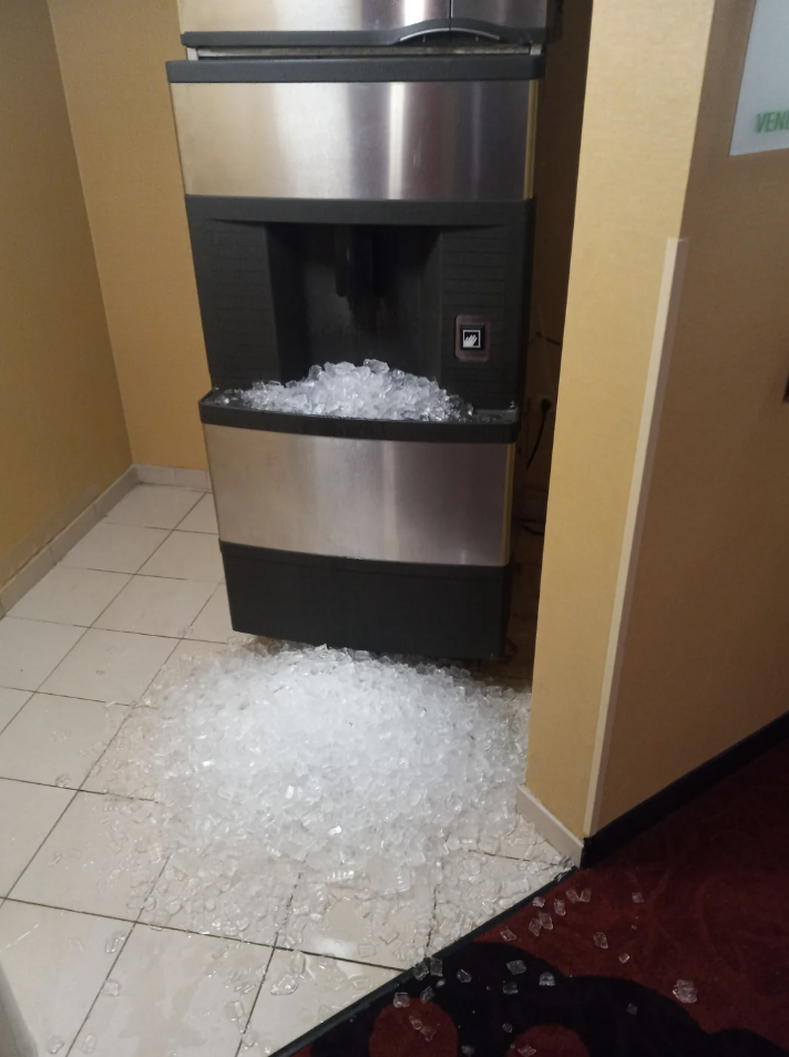 Ice machine malfunctioning, spilling ice onto the floor in a hallway