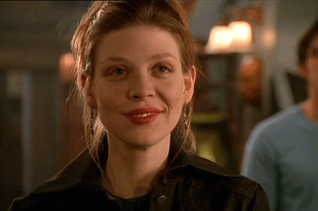 Amber Benson smiling while wearing a dark jacket indoors