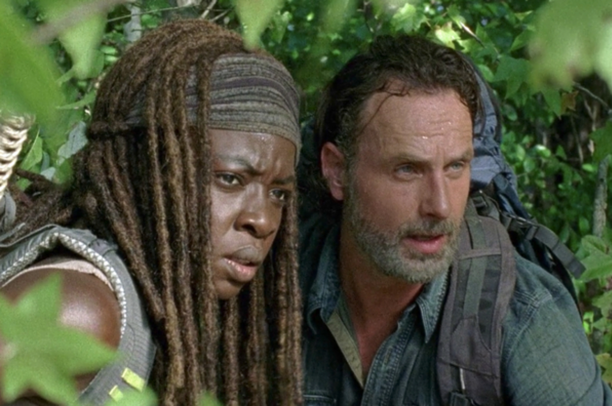 Danai Gurira and Andrew Lincoln, seen outdoors among foliage, in a scene from a TV show. They appear alert and focused
