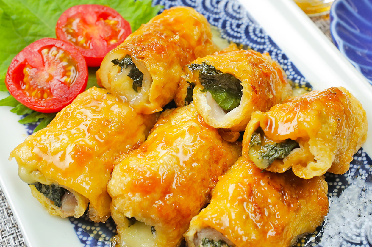 和風ソースでグリルされた肉巻きシソとトマトの飾りが添えられた美味しそうな料理。右上には飲み物が見える。