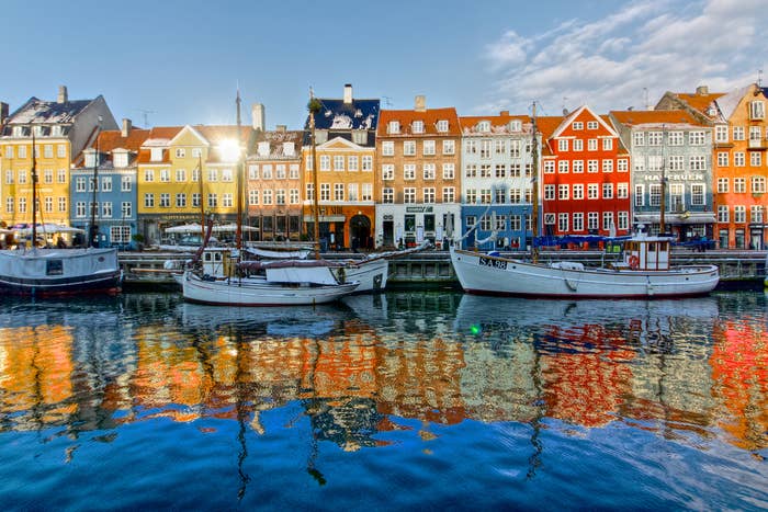 Boats docked along a canal with colorful historic buildings in the background in Copenhagen, Denmark