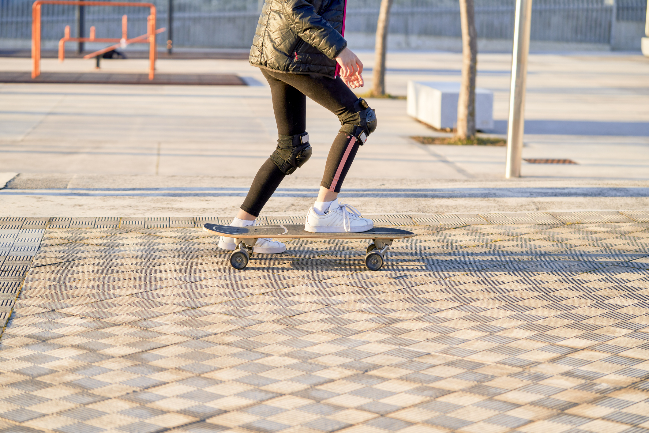 Person skateboarding outdoors, wearing protective gear and casual clothing