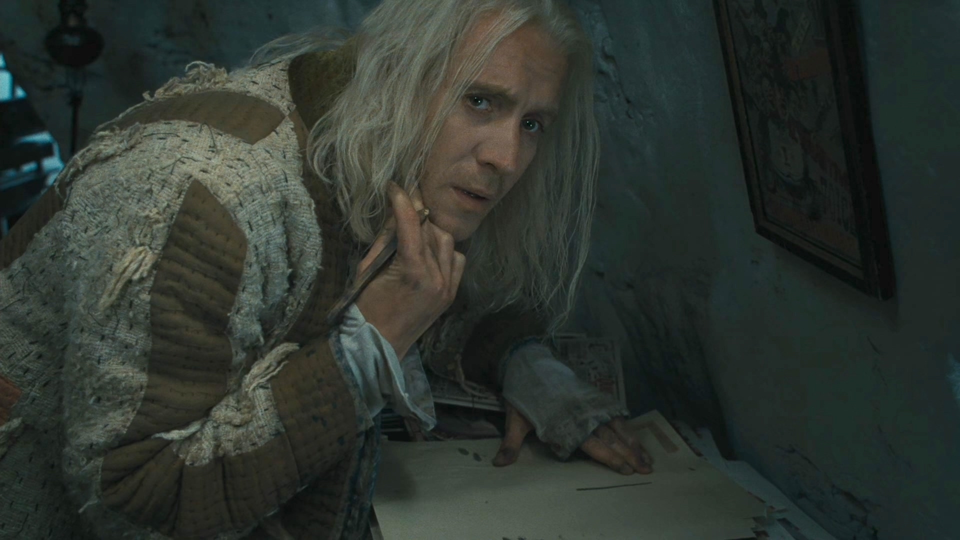 Henry Cavill as Geralt of Rivia, in "The Witcher," dressed in tattered medieval clothing, looking at the camera while his hand rests on a document