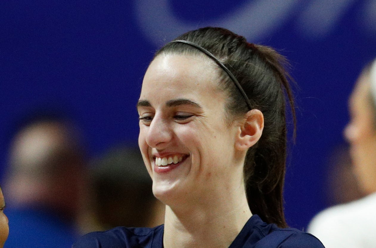 Kelsey Mitchell laughs with Victoria Vivians during a warm-up session, surrounded by other athletes on a basketball court