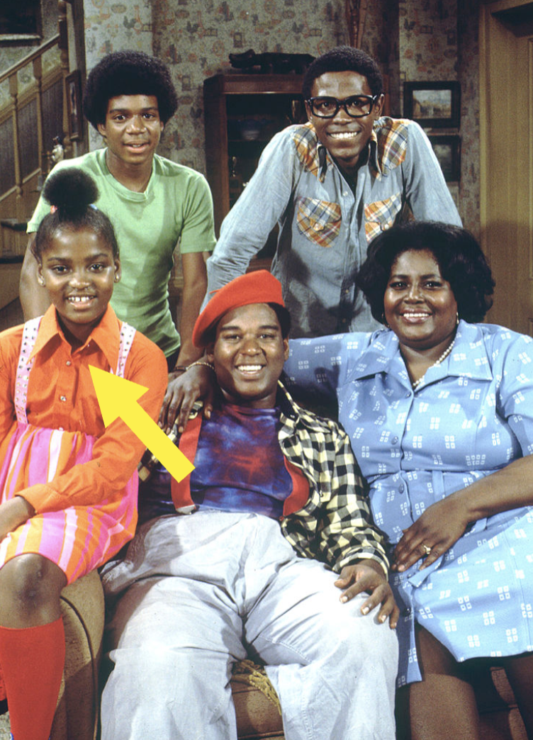 The image shows a group of five people posing together, with a large arrow pointing to a girl in a bright, striped outfit