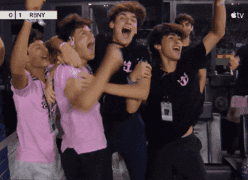 Group of five young men jump and cheer with excitement in stadium seats while watching a soccer game