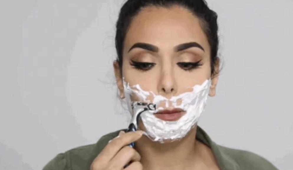 Huda Kattan shaves her face with a razor