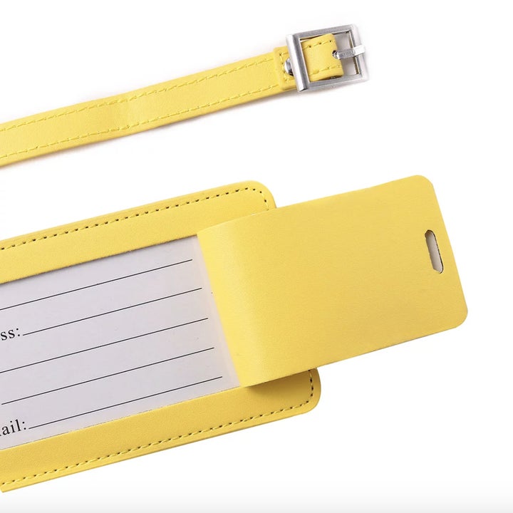 Yellow luggage tag with a buckled strap, featuring an insert for contact details including name, address, and email