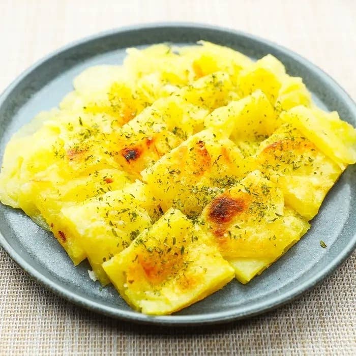 焼きポテトが皿に盛られており、ハーブがトッピングされています。