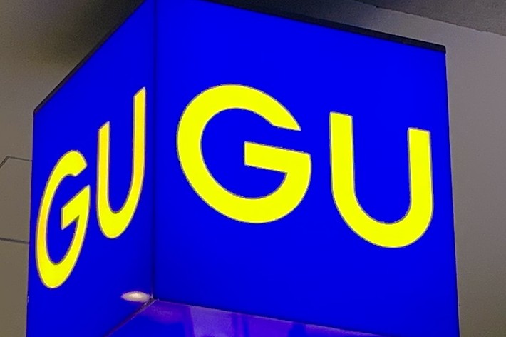 Sign with the letters &ldquo;GU&rdquo; in yellow on a blue background, seen hanging from a ceiling