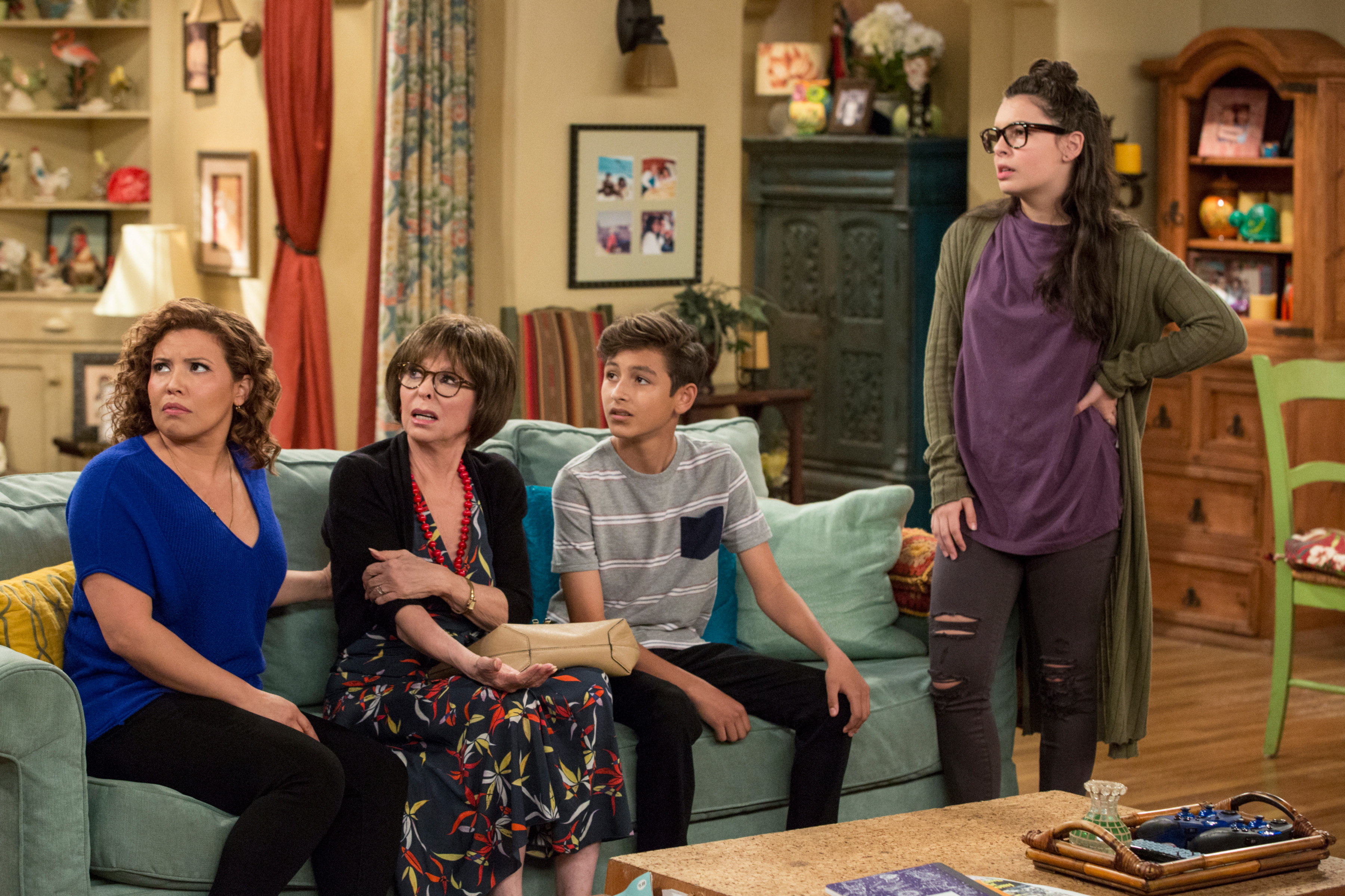 Justina Machado, Rita Moreno, Marcel Ruiz, and Isabella Gomez in a living room in a scene from &quot;One Day At a Time&quot;
