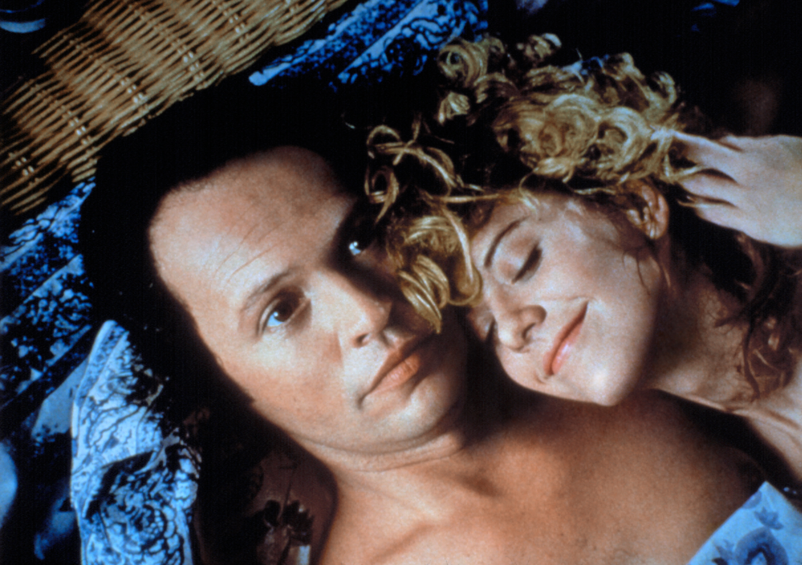Billy Crystal and Meg Ryan in a close-up scene, lying together. Meg Ryan rests her head on Billy Crystal's chest, both with content expressions in "When Harry Met Sally…"