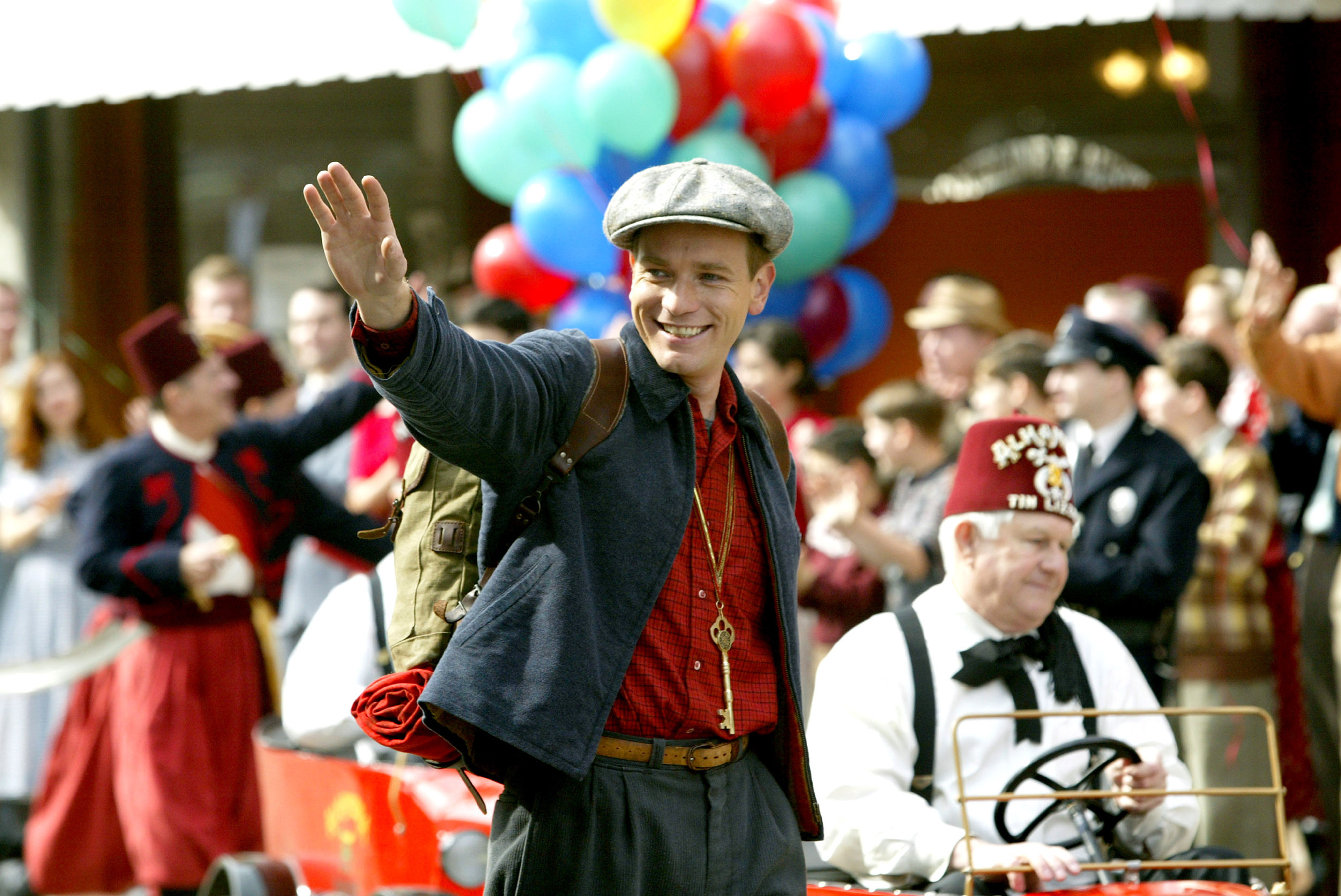 Ewan McGregor waving with a crowd of people in the background in a scene from "Big Fish"