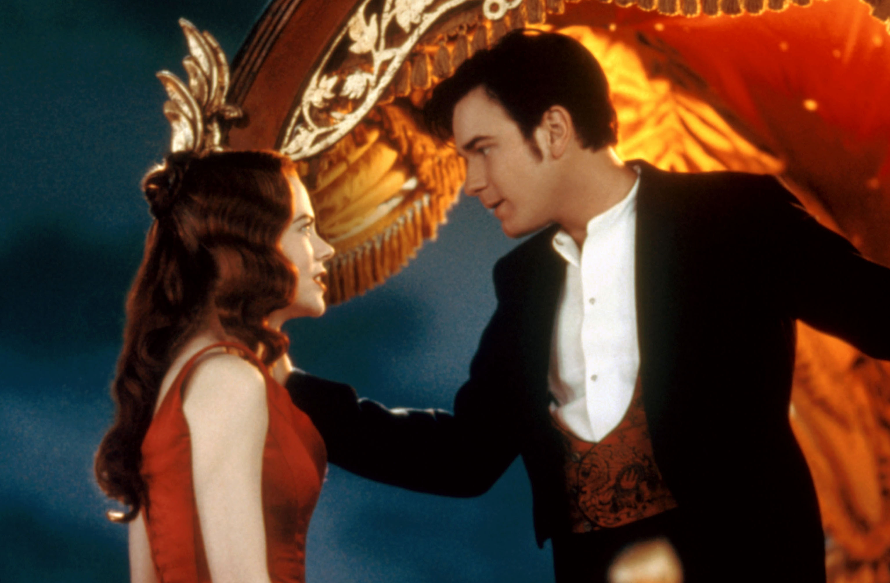 Nicole Kidman in a red dress and Ewan McGregor in a formal suit with a red vest in a scene from the movie "Moulin Rouge!"