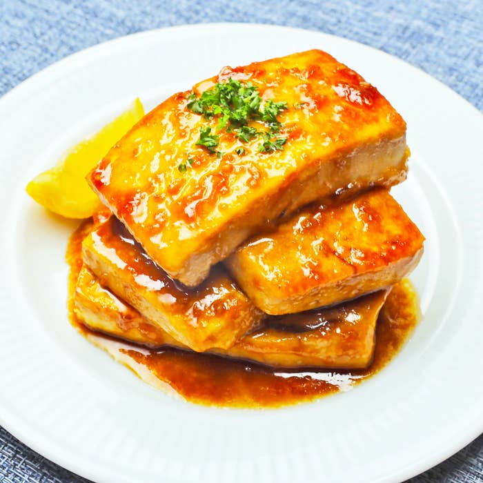 白い皿に乗った照り焼き豆腐の盛り合わせ。上にはみじん切りのパセリが添えられ、横にはレモンのくし切りが置かれています。