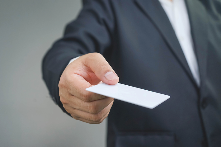 ビジネスマンが白い名刺を差し出している。
