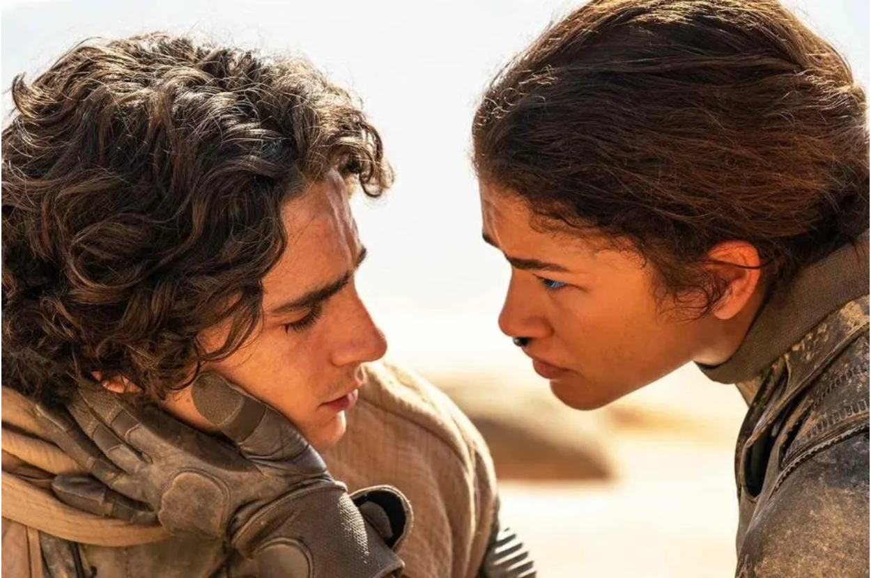 Timothée Chalamet and Zendaya in a close-up scene from the movie "Dune," with intense expressions and wearing desert attire