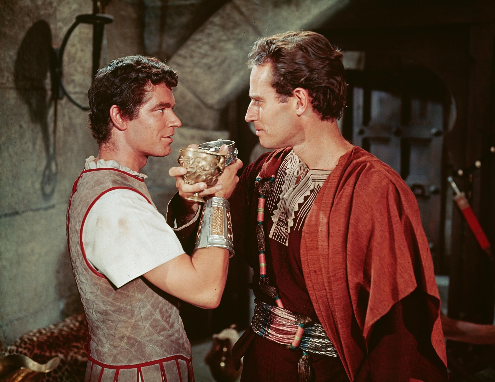 Stephen Boyd and Charlton Heston in a scene from the movie "Ben-Hur," dressed in Roman-style attire and holding a cup together