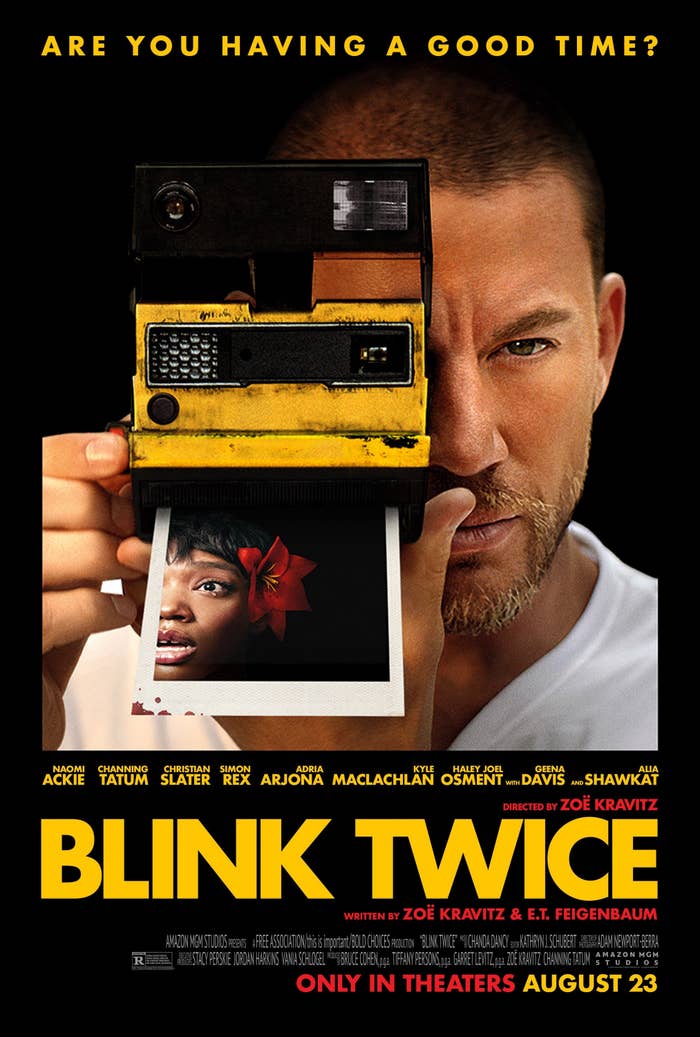 A man holds a yellow Polaroid camera that reveals a photo of a surprised woman with a flower in her hair. The poster text reads: "Are you having a good time? Blink Twice. In theaters August 23."