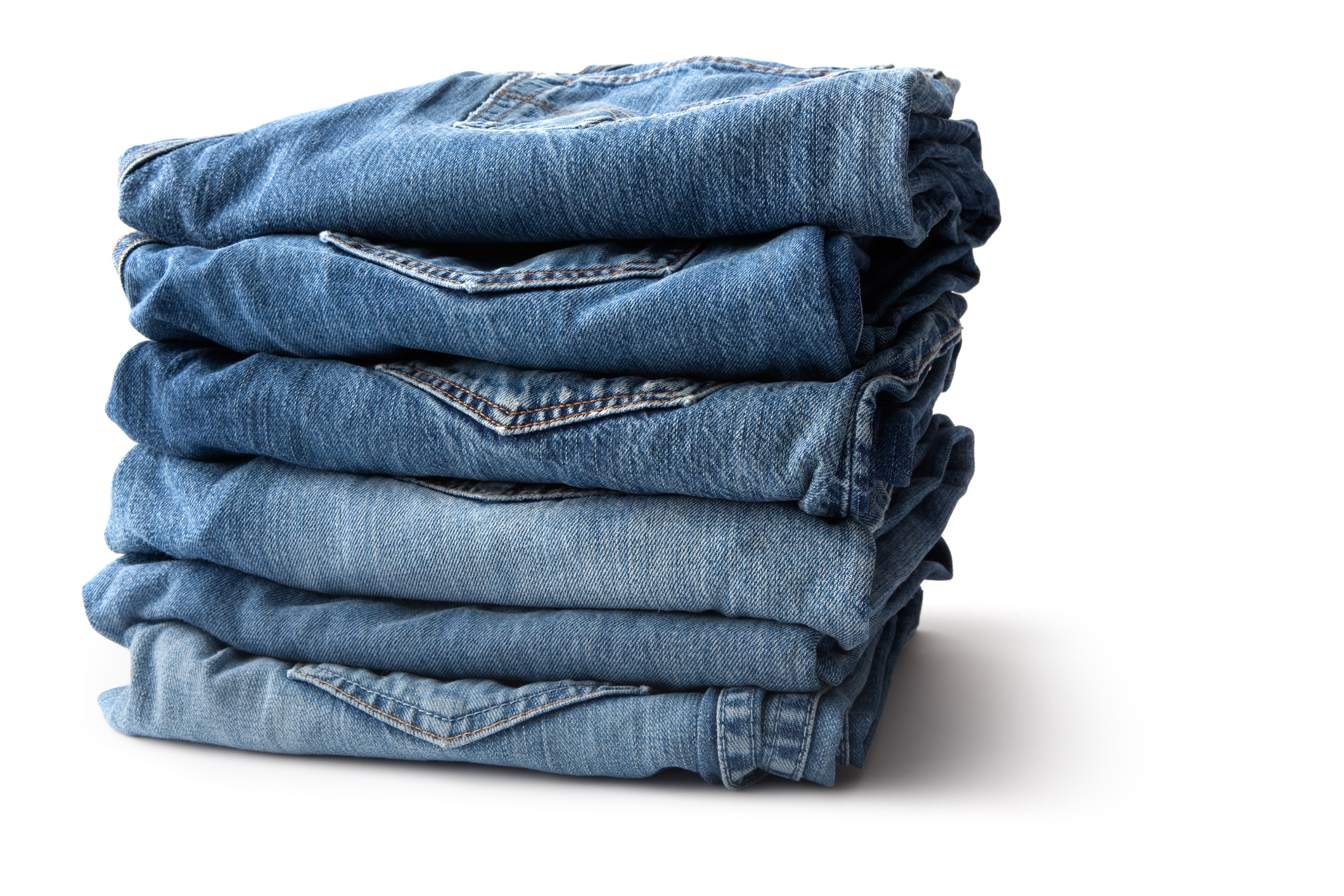 A neatly folded stack of blue jeans on a white background. There are no individuals in this image