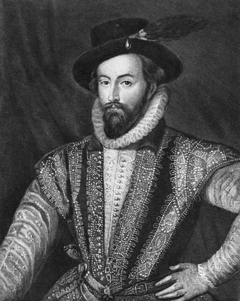 A historic illustration of Sir Walter Raleigh wearing period attire with intricate patterns and a ruffled collar, posed with one arm on his hip