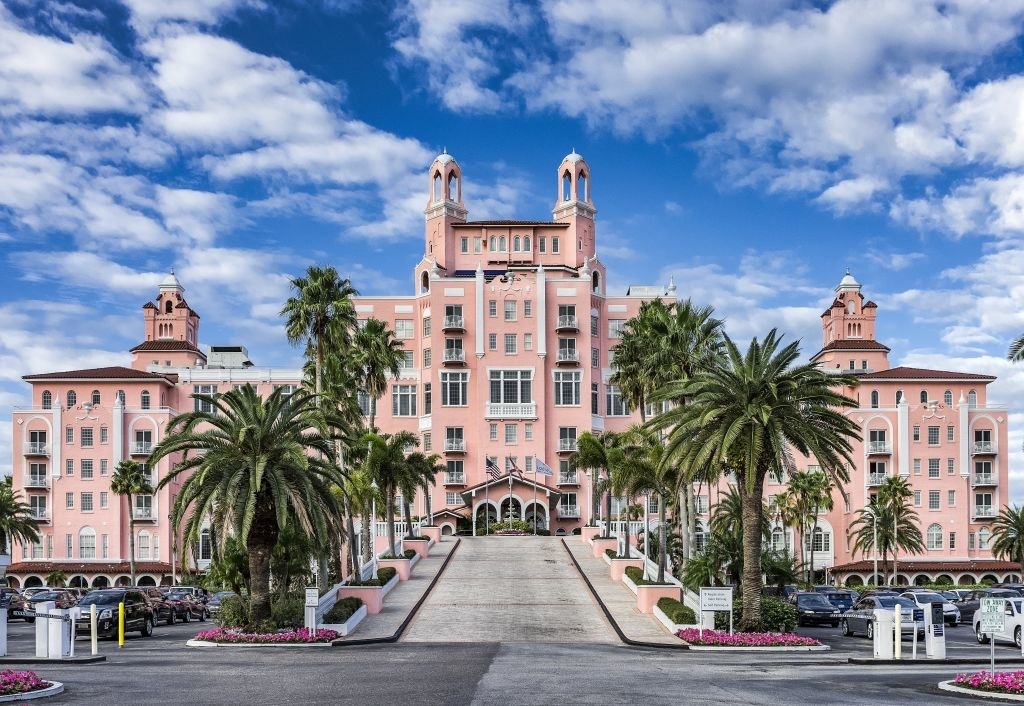 A grand view of the historic Don CeSar Hotel, also known as the &quot;Pink Palace,&quot; showing its detailed architecture, palm trees, and symmetrical landscaping