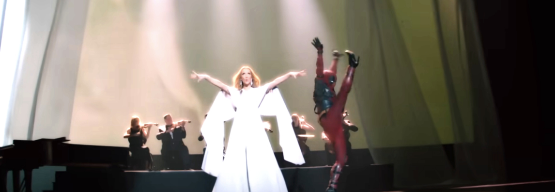 Celine Dion and Deadpool perform on stage, with musicians playing instruments in the background. Celine is in an elegant gown and Deadpool is mid-kick in his costume